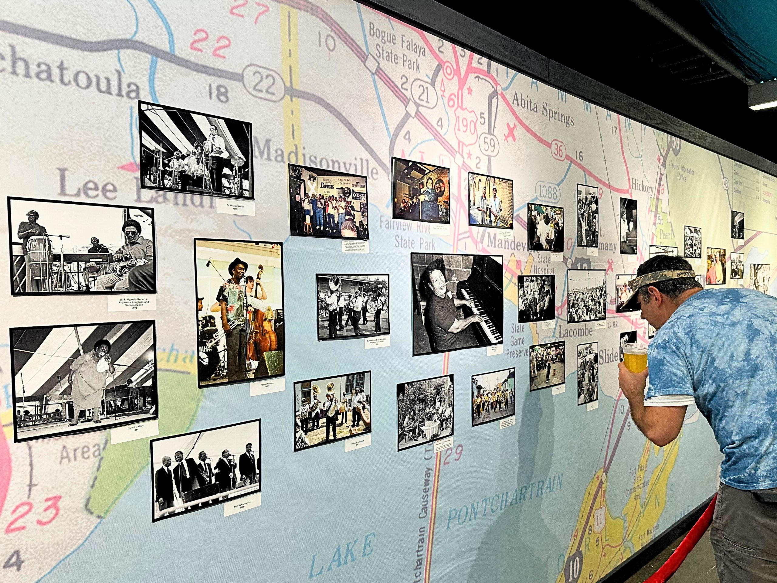 New Orleans Jazz Fest Photo Archive. A man standing looking at photos on the wall.